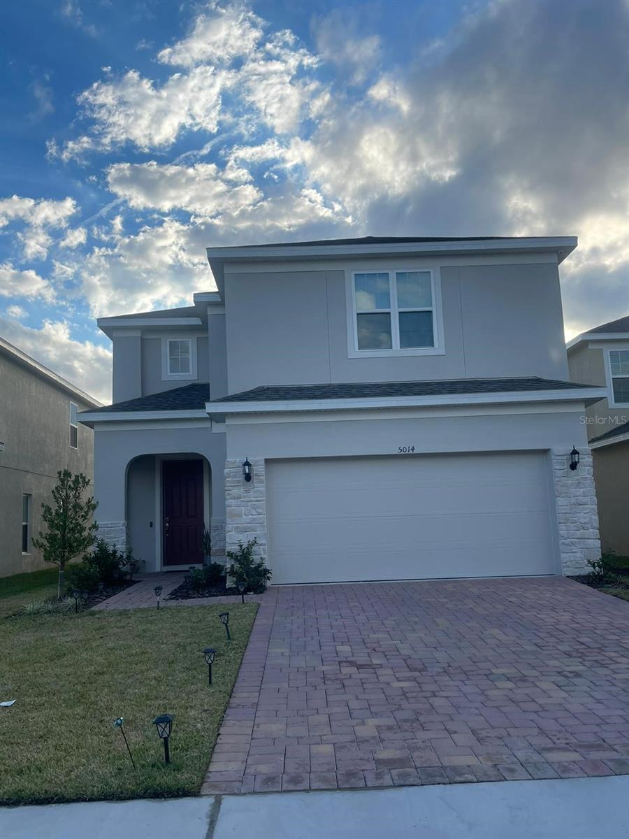 5014 Royal Point Ave, Kissimmee, FL 34746 - traditional home featuring a front yard, stone siding, a garage, stucco siding, and decorative driveway