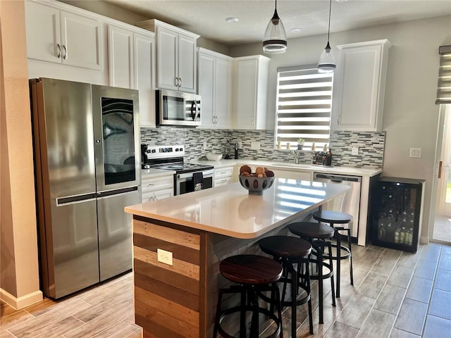 11826 Sky Acres Ter, Bradenton, FL 34211 - kitchen with stainless steel appliances, wood tiled floors, a center island, light countertops, and white cabinetry