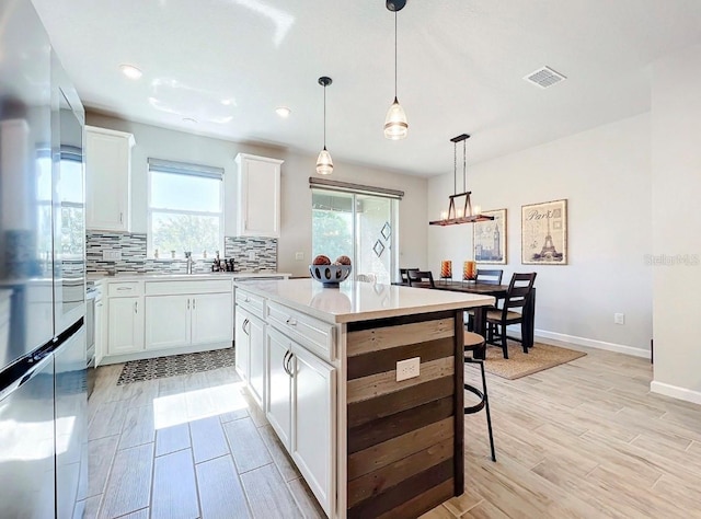 11826 Sky Acres Ter, Bradenton, FL 34211 - kitchen with stainless steel refrigerator, tasteful backsplash, light countertops, a center island, and white cabinets