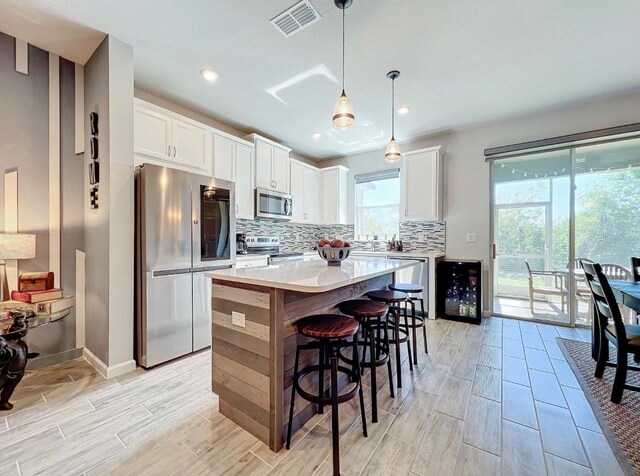 11826 Sky Acres Ter, Bradenton, FL 34211 - kitchen featuring stainless steel appliances, decorative backsplash, white cabinets, wine cooler, and a center island