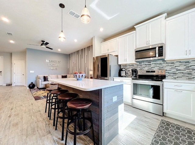 11826 Sky Acres Ter, Bradenton, FL 34211 - kitchen with stainless steel appliances, a kitchen island, open floor plan, decorative backsplash, and white cabinetry