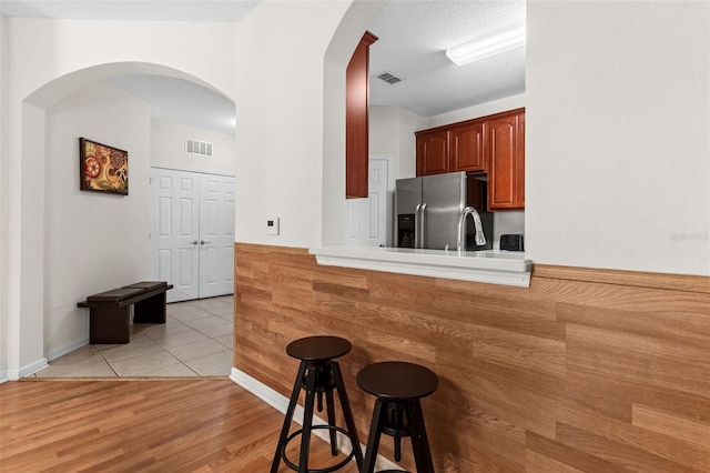 4114 Breakview Dr Unit 11002, Orlando, FL 32819 - kitchen featuring a breakfast bar area, visible vents, stainless steel refrigerator with ice dispenser, and light wood-style floors
