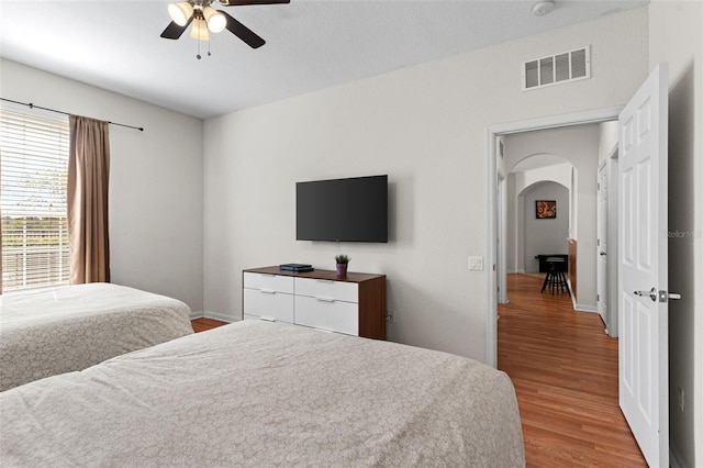 4114 Breakview Dr Unit 11002, Orlando, FL 32819 - bedroom featuring baseboards, arched walkways, light wood finished floors, ceiling fan, and visible vents