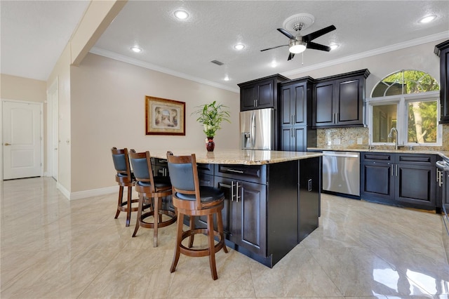 2910 Frontier Dr, Kissimmee, FL 34744 - kitchen featuring ceiling fan, a breakfast bar area, a kitchen island, appliances with stainless steel finishes, and a sink