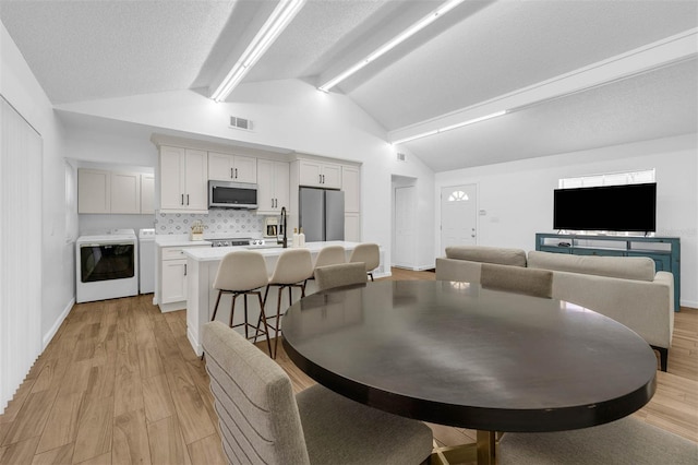 4066 Vanet Ct, Orlando, FL 32822 - dining area featuring light wood finished floors, beamed ceiling, visible vents, and washing machine and clothes dryer