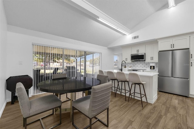 4066 Vanet Ct, Orlando, FL 32822 - dining area featuring baseboards, visible vents, vaulted ceiling, and light wood finished floors