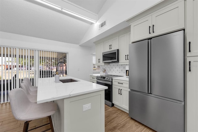 4066 Vanet Ct, Orlando, FL 32822 - kitchen with visible vents, stainless steel appliances, lofted ceiling, a sink, and a breakfast bar area