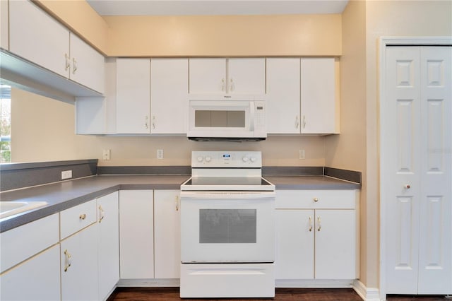 kitchen with dark wood-style flooring, white cabinetry, dark countertops, and white appliances
