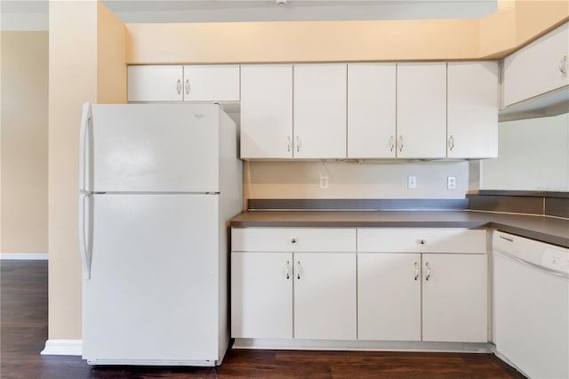 kitchen with dark wood-type flooring, white cabinetry, dark countertops, and white appliances