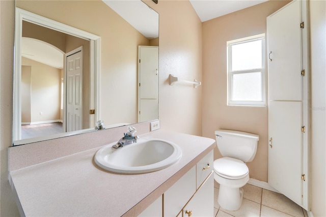 half bathroom with tile patterned flooring, vanity, and toilet