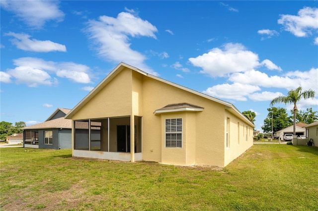 back of property featuring a sunroom, stucco siding, and a yard
