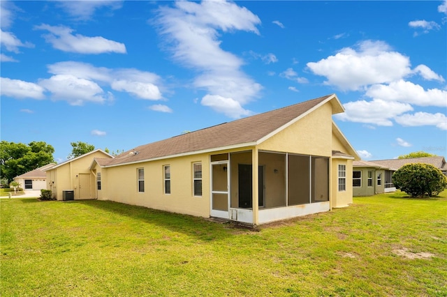 back of house featuring a lawn, stucco siding, a sunroom, and central AC