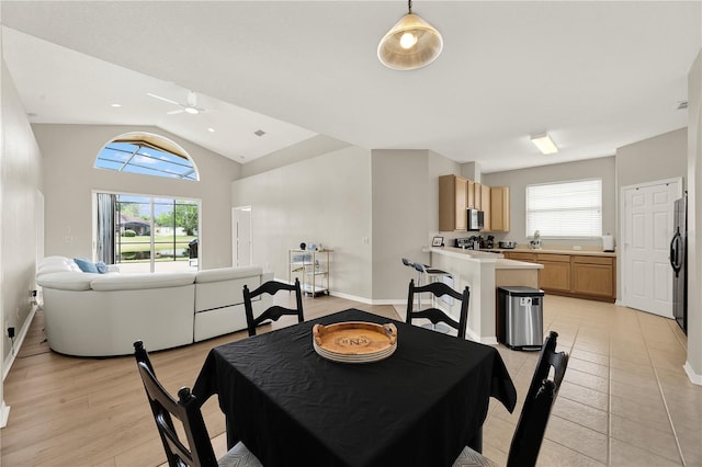 dining space with baseboards, vaulted ceiling, ceiling fan, and a healthy amount of sunlight