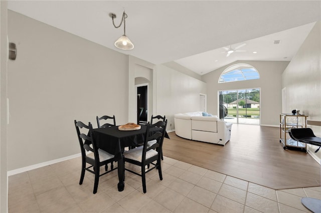 dining area with high vaulted ceiling, light wood-style floors, baseboards, arched walkways, and ceiling fan