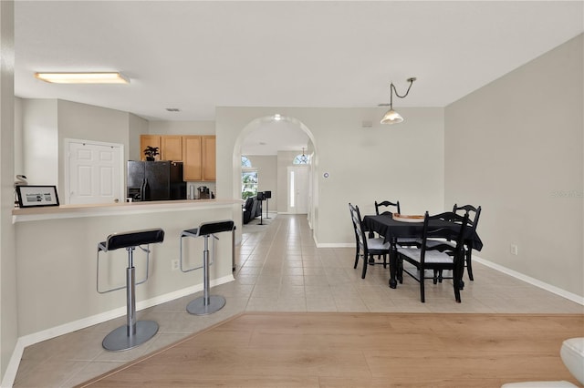 dining area with arched walkways, visible vents, baseboards, and light tile patterned floors