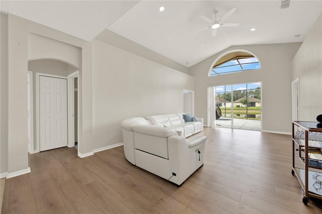 living room featuring arched walkways, a ceiling fan, baseboards, and light wood-type flooring