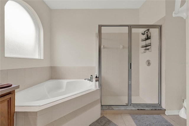 full bath featuring tile patterned flooring, a bath, and a shower stall