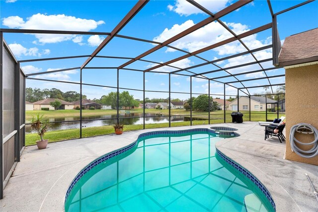 view of pool with a pool with connected hot tub, a lanai, a water view, and a patio area