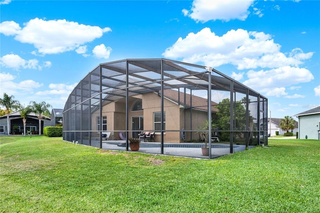 back of house with glass enclosure, a patio, and a yard