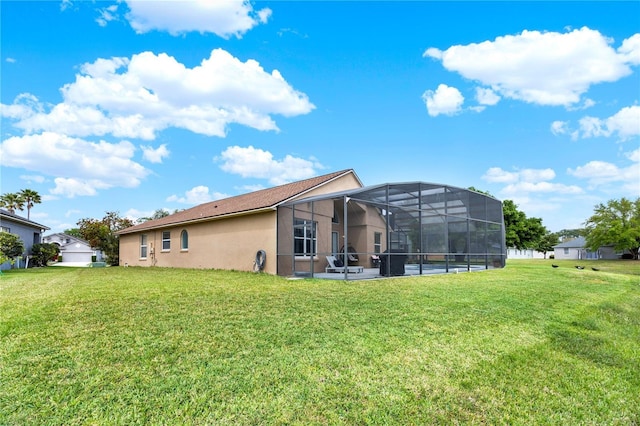 rear view of property with glass enclosure, a lawn, and stucco siding
