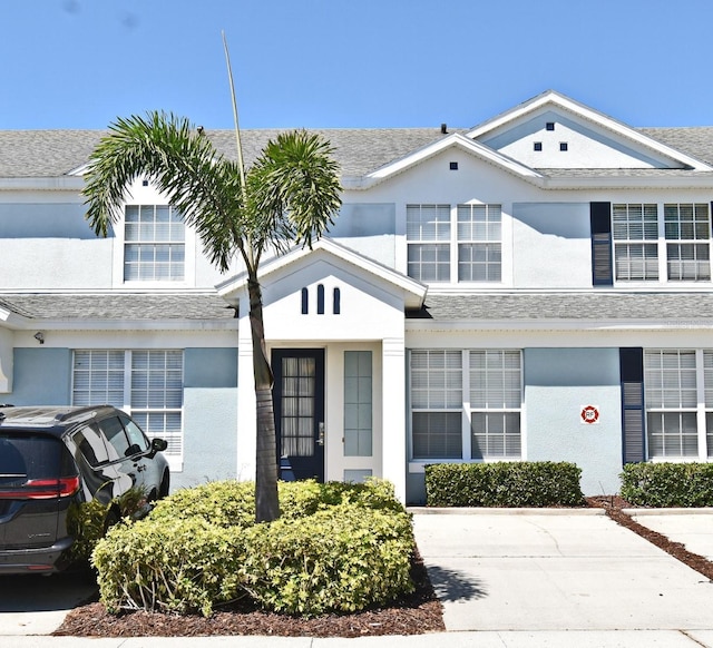 view of front of house featuring stucco siding and roof with shingles