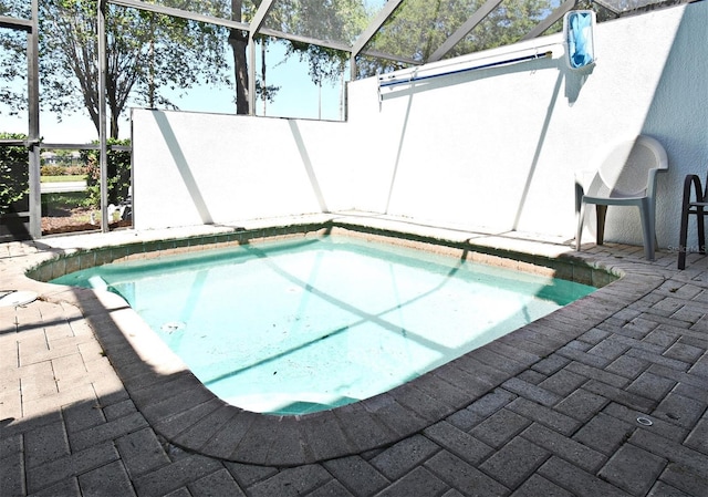outdoor pool with glass enclosure and a patio area