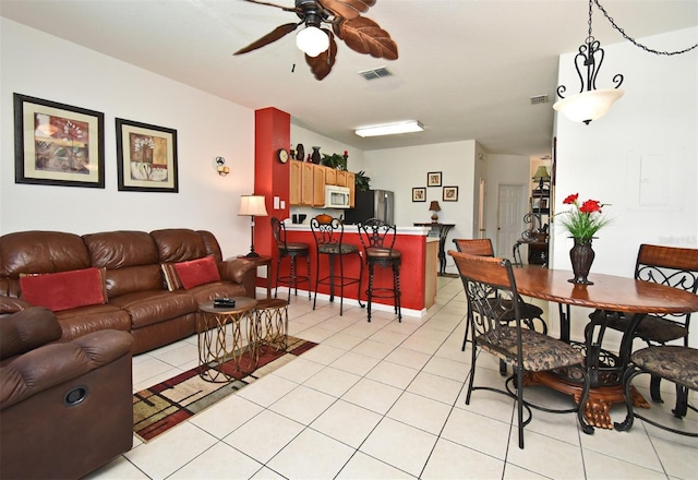 living area featuring ceiling fan, visible vents, and light tile patterned floors