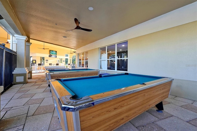 game room with decorative columns, stone tile floors, a ceiling fan, and billiards