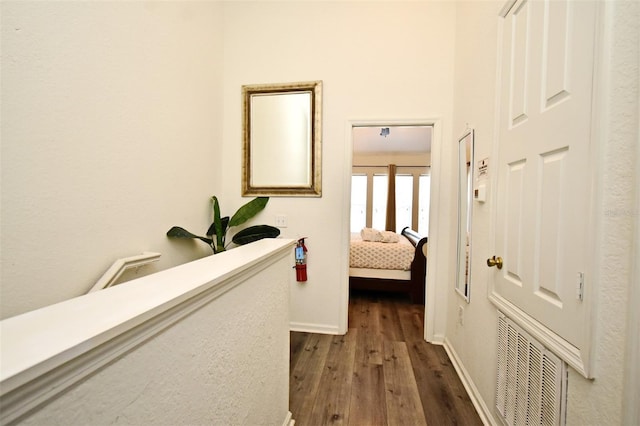 hallway with baseboards, visible vents, and dark wood-style flooring