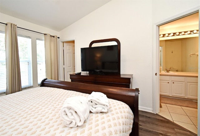 bedroom with a sink, lofted ceiling, tile patterned flooring, and ensuite bathroom