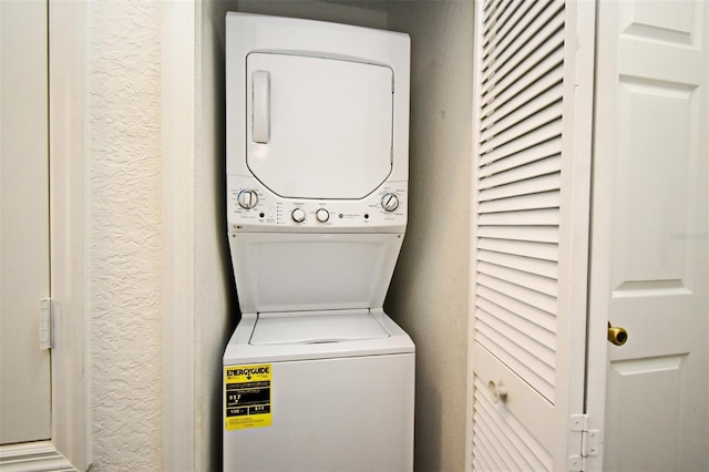 clothes washing area with stacked washer and dryer, a textured wall, and laundry area