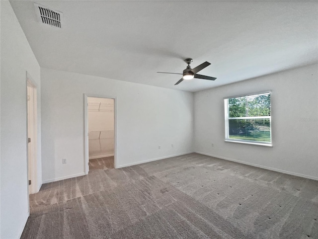 carpeted empty room with a ceiling fan, baseboards, and visible vents