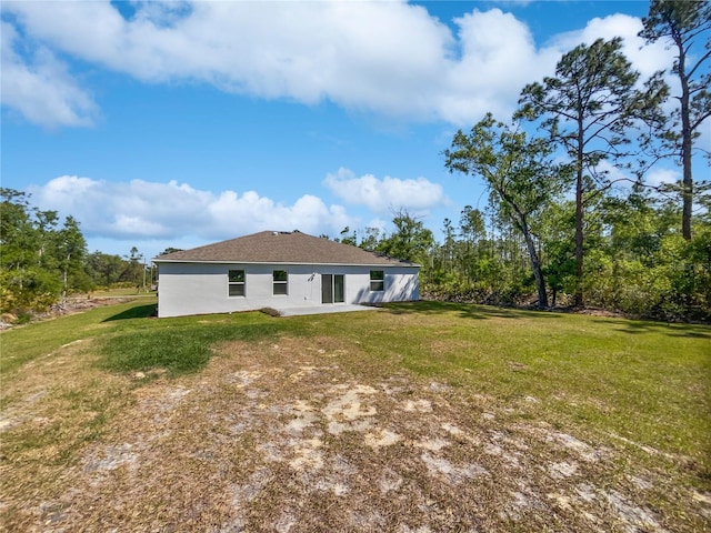 back of house featuring a lawn, stucco siding, and a patio