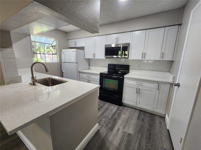kitchen featuring stainless steel microwave, dark wood-style flooring, a sink, freestanding refrigerator, and black electric range