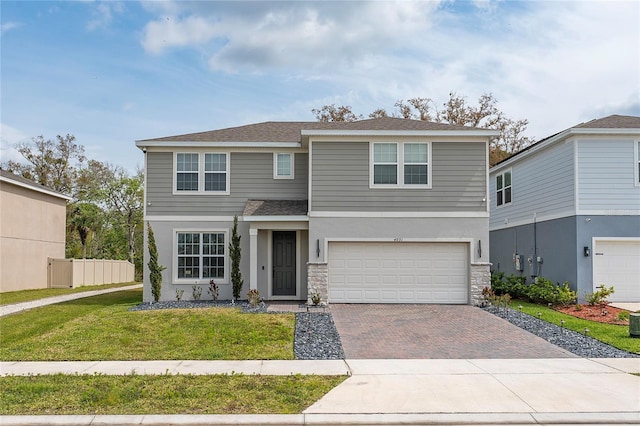 4991 Royal Point Ave, Kissimmee, FL 34746 - traditional home featuring stone siding, an attached garage, a front yard, roof with shingles, and driveway