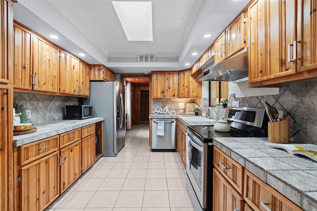 kitchen with a sink, visible vents, appliances with stainless steel finishes, under cabinet range hood, and light tile patterned floors