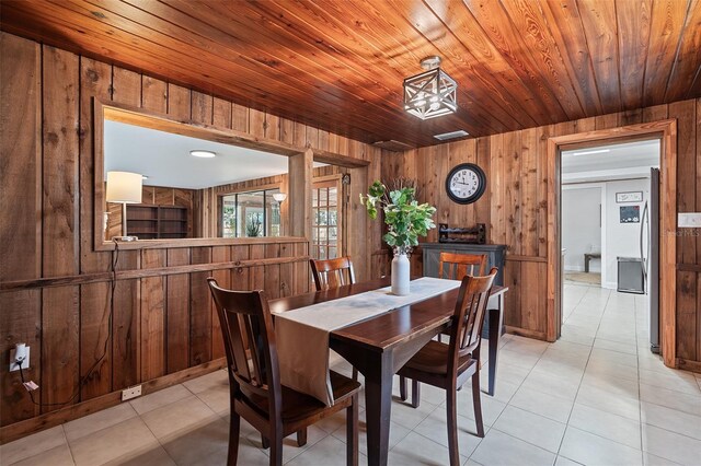 dining space with wood ceiling, wood walls, and light tile patterned floors