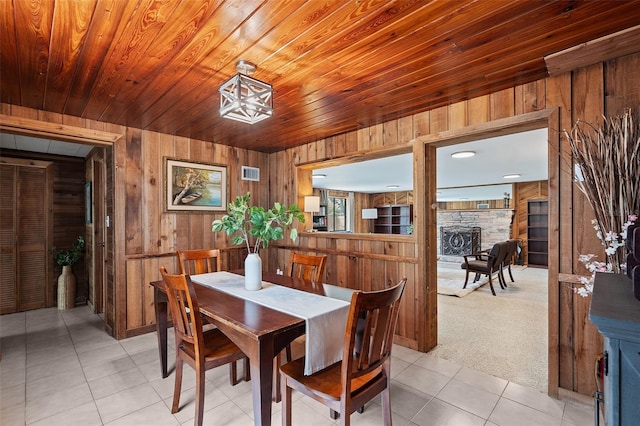 dining area featuring light tile patterned flooring, visible vents, wood walls, and wood ceiling