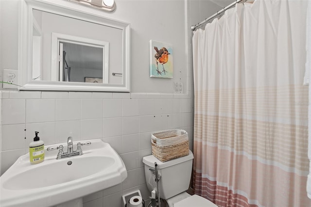 full bath with a sink, tile walls, a wainscoted wall, toilet, and a shower with shower curtain