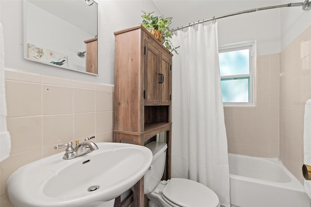 full bath featuring tile walls, shower / bath combination with curtain, a sink, and toilet