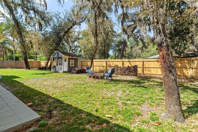 view of yard featuring a fenced backyard, a storage unit, and an outbuilding