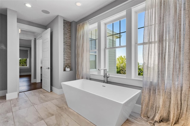 1224 Union Club Dr, Winter Garden, FL 34787 - bathroom featuring healthy amount of natural light, a freestanding tub, baseboards, recessed lighting, and marble look tiles