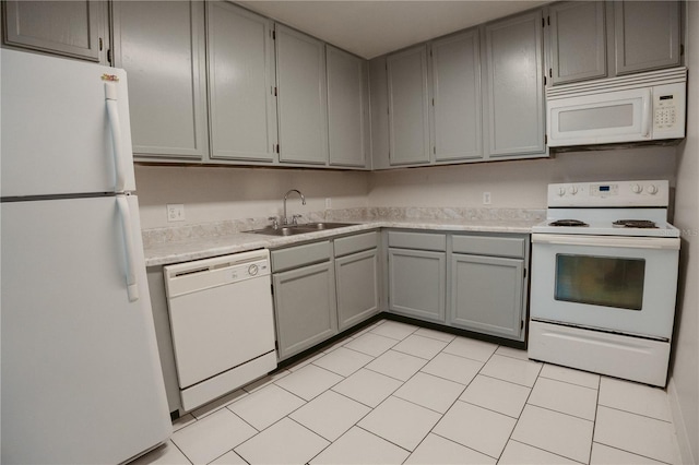 kitchen featuring light countertops, a sink, gray cabinets, and white appliances