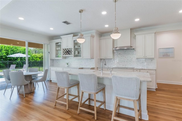 11826 Fiore Dr, Orlando, FL 32827 - kitchen with a breakfast bar, a sink, light wood-style floors, wall chimney range hood, and white cabinets