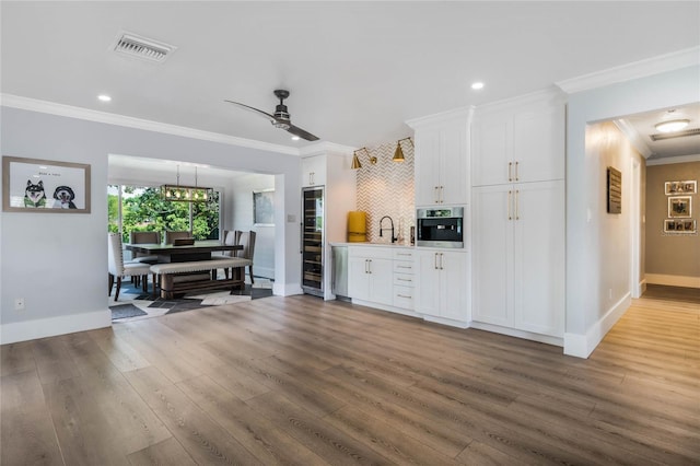 201 Cedarwood Dr, Maitland, FL 32751 - kitchen featuring crown molding, white cabinetry, wood finished floors, visible vents, and oven