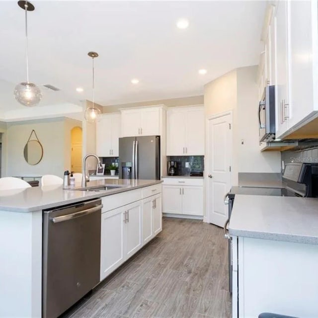 14711 Winter Stay Dr, Winter Garden, FL 34787 - kitchen with stainless steel appliances, a sink, a kitchen island with sink, backsplash, and white cabinetry