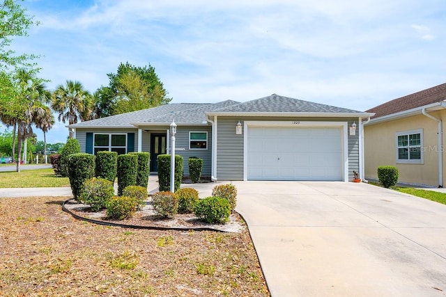 single story home with driveway, a shingled roof, and an attached garage
