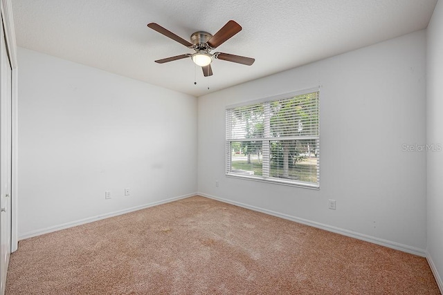 empty room featuring baseboards, a textured ceiling, carpet flooring, and a ceiling fan