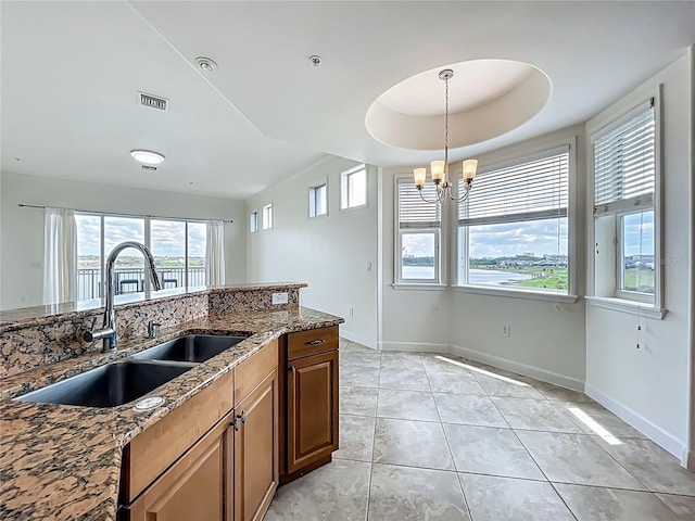 8743 S The Esplanade Unit 18, Orlando, FL 32836 - kitchen featuring a chandelier, stone counters, decorative light fixtures, brown cabinets, and light tile patterned floors