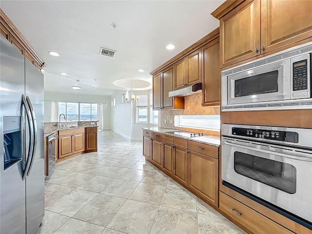 8743 S The Esplanade Unit 18, Orlando, FL 32836 - kitchen with stainless steel appliances, tasteful backsplash, under cabinet range hood, light stone countertops, and recessed lighting
